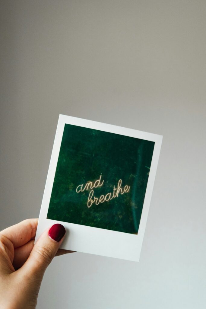 A hand holding a polaroid that reads breathe